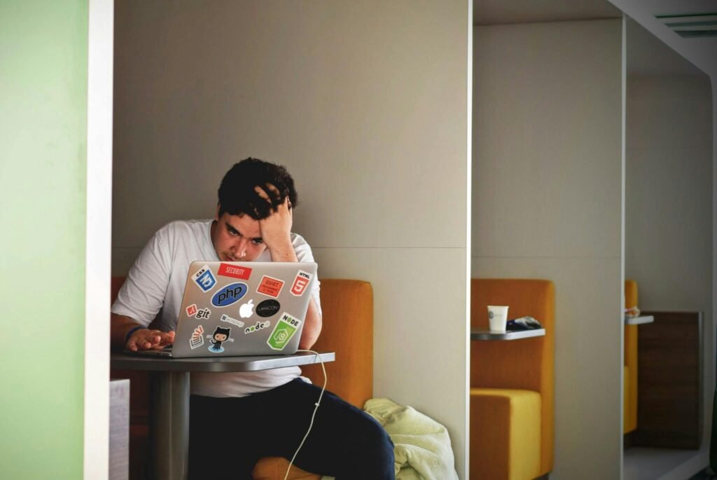 pexels-photo-52608-52608 Man showing stress and frustration while working remotely on a laptop indoors.